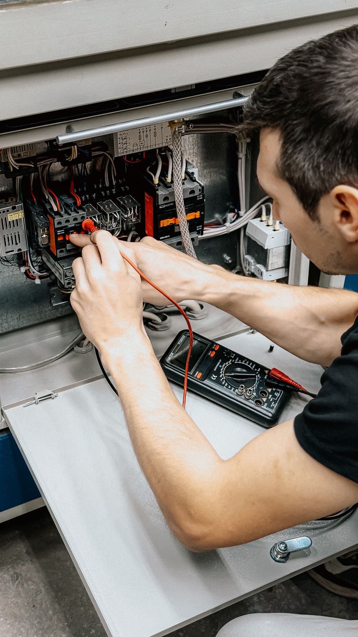 Technician testing an industrial electrical panel
